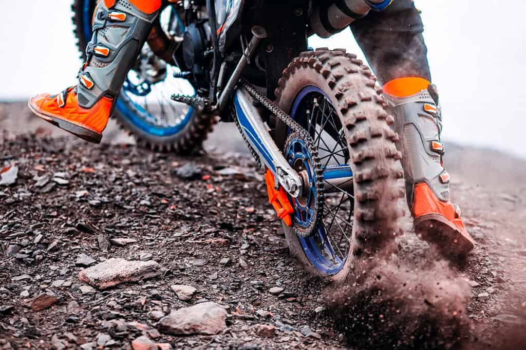 Photo of a dual sport motorcycle tire digging into gravel on off-road terrain